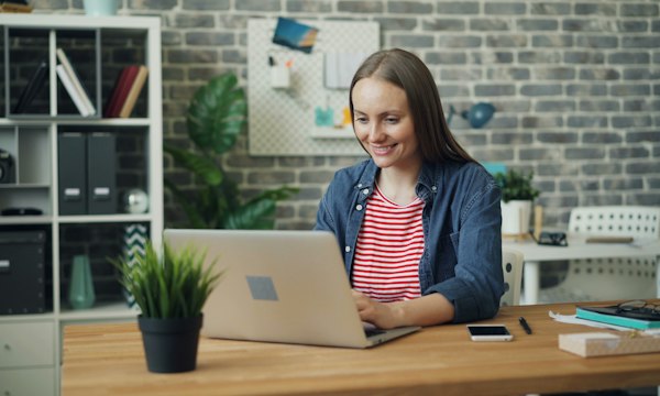 Cliente souriante devant son ordinateur portable